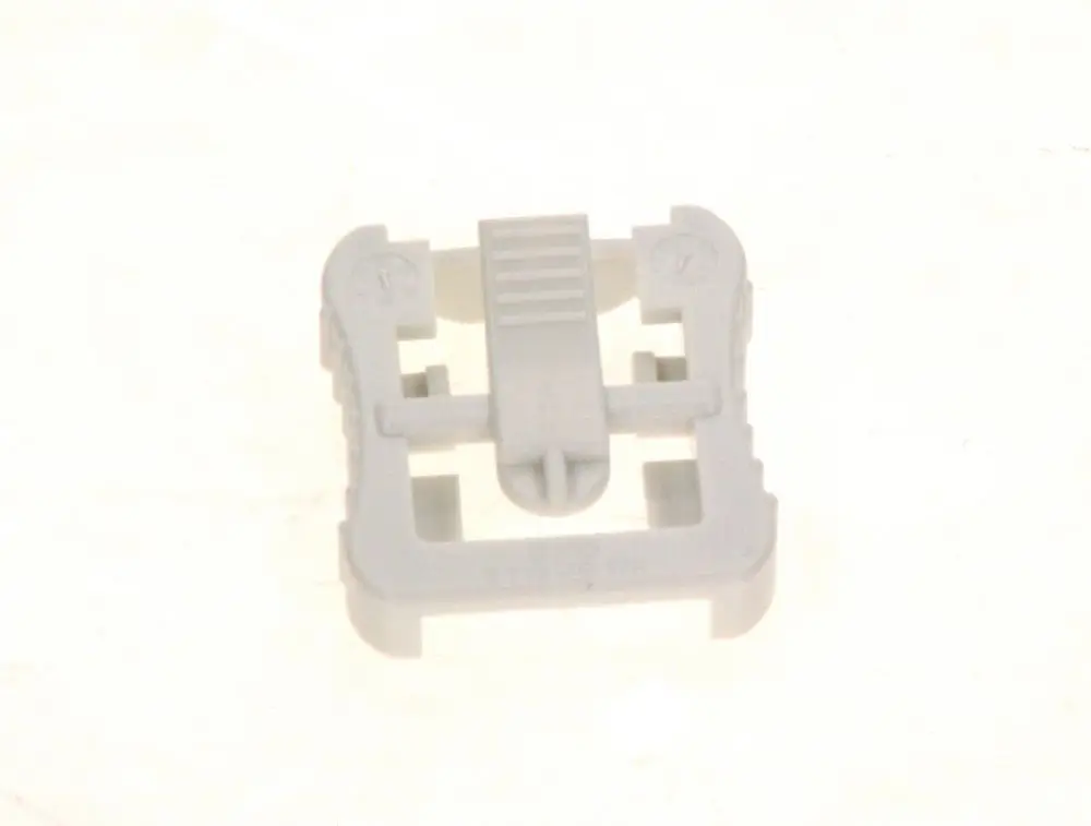 Weißer Plastikclip von Bosch mit Befestigungselement. Das Produkt hat eine quadratische Form und eine zentrale Haltevorrichtung.